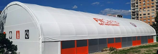 Biela moderná krytá hala FitCamp v Ružinove s logom "Get Motivated", v ktorej sa nachádzajú celoročné padelové kurty.
